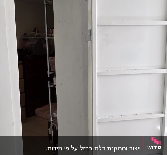 דלת מתכת לבנה פתוחה בחדר פנימי